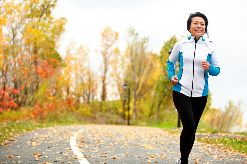 Mature woman running with fall leaves